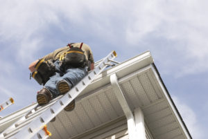 Worker repairing gutters on ladder